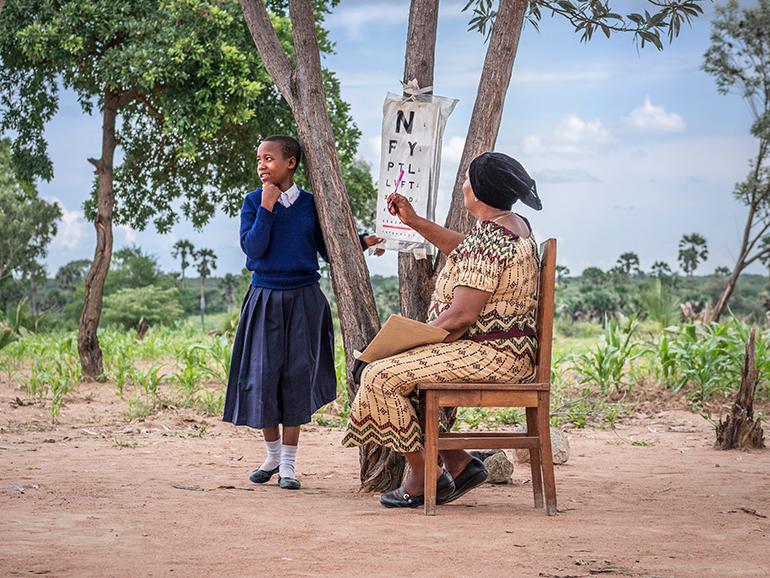 Tanzanian schoolgirl and outreach outreach worker with Echart at a school screening