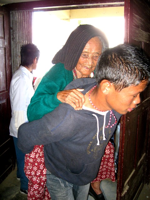 The burden of cataract blindness... a teenage boy carries his blind grandmother to have her eyes examined by the Seva team