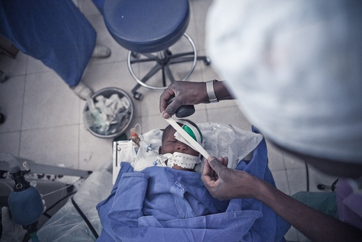 Surgeon applying eye patch to child after cataract surgery in Malawi