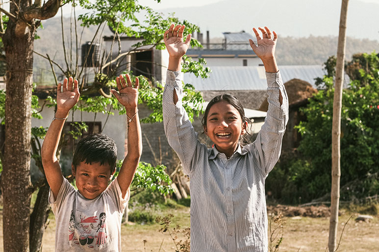 Two Nepali kids with their hands in the air